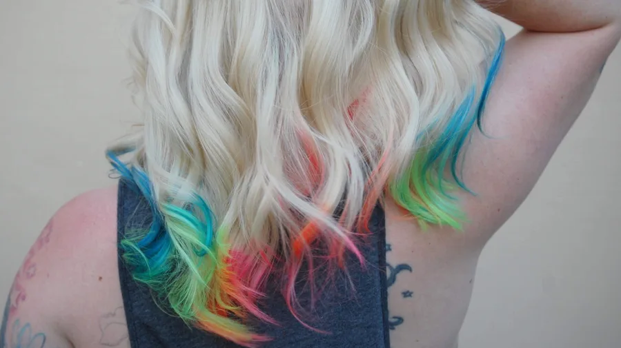 Blonde hair lifted to show a rainbow colored underlayer beneath