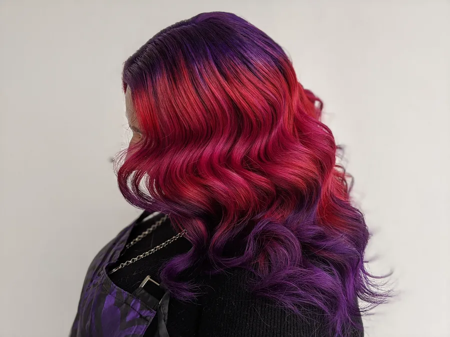 Long wavy hair colored from deep red at the roots through to violet ends